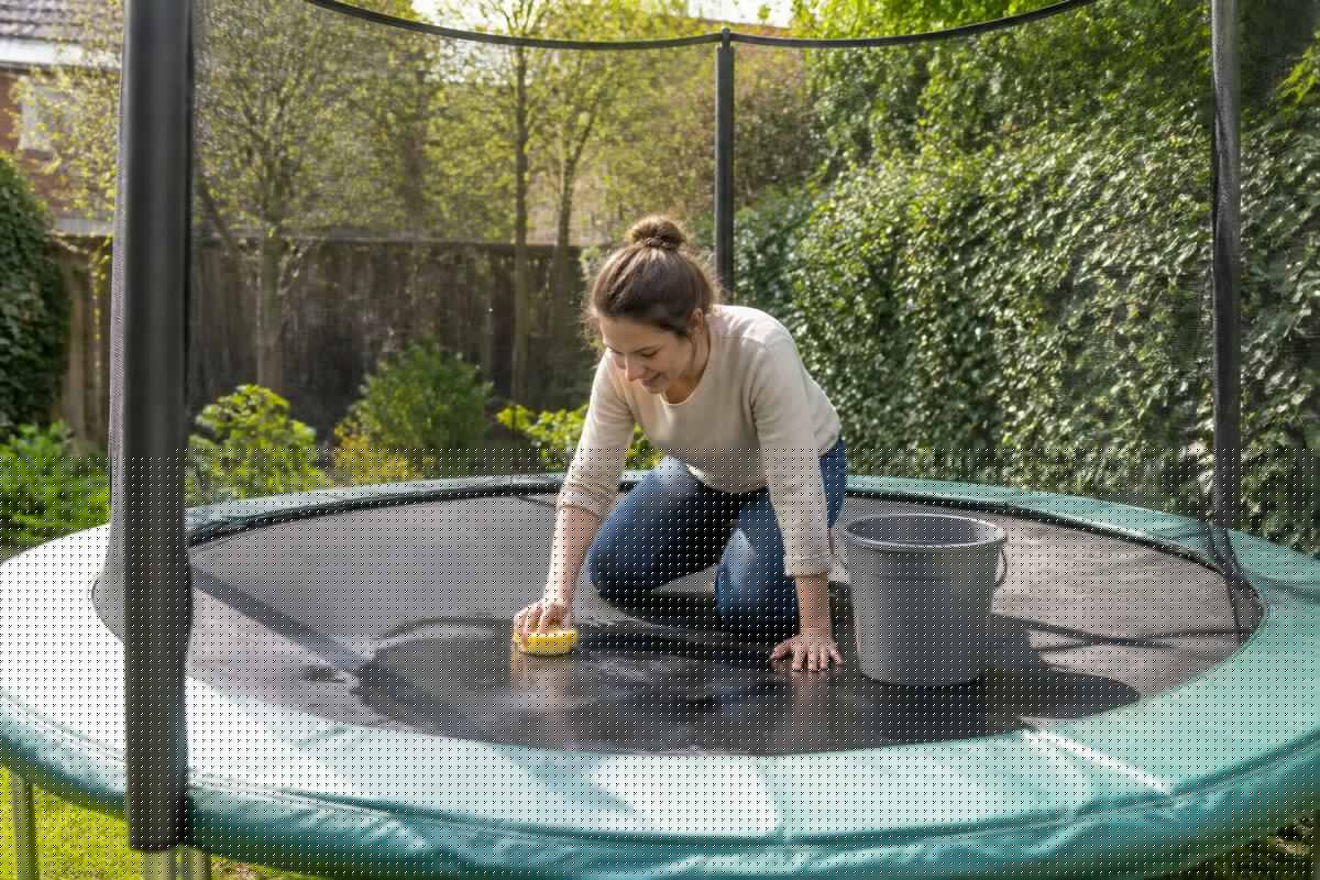 Trampoline in de tuin wordt schoongemaakt met een zachte spons