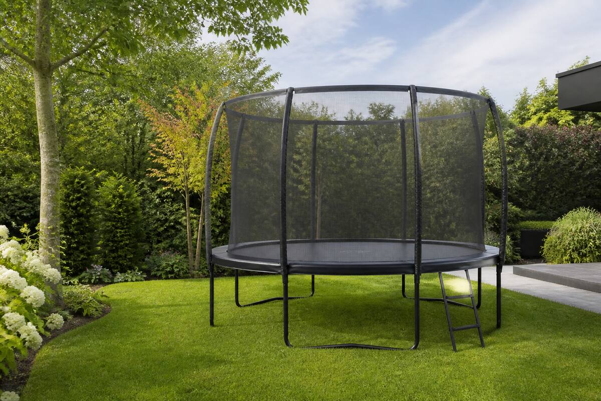 Trampoline met veiligheidsnet in een verzorgde tuin